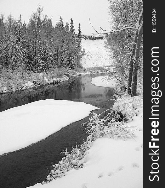 A part-frozen river meanders through a snowy landscape. A part-frozen river meanders through a snowy landscape.