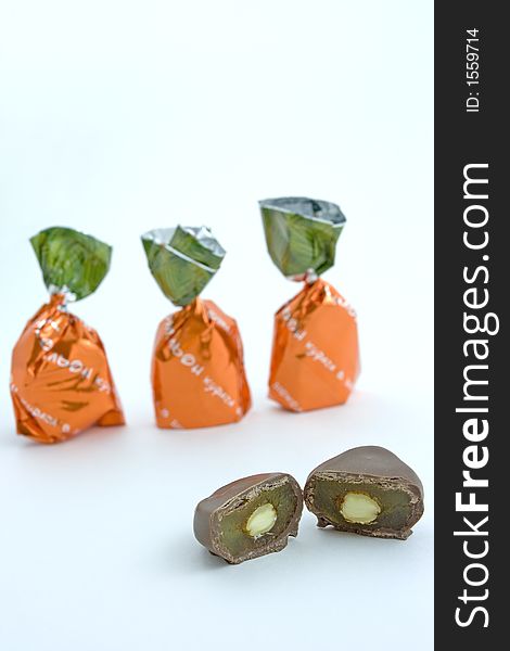 A sliced chocolate candy with almond and dried apricot filling and more wrapped candies on the back