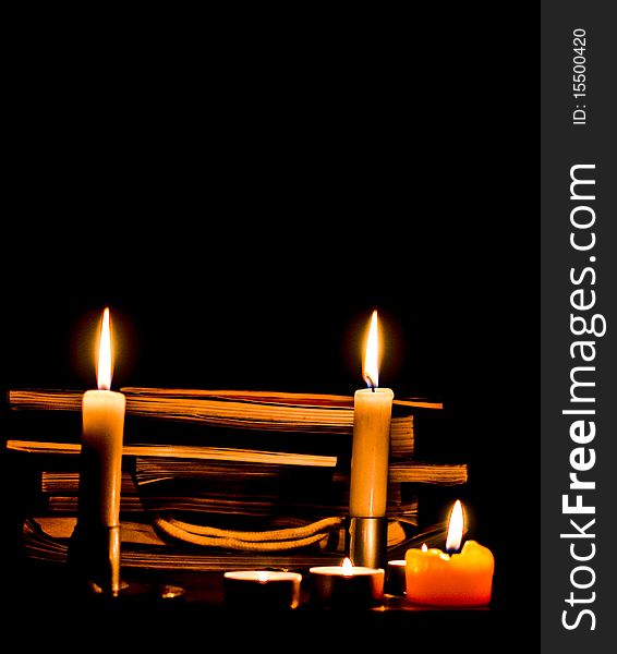 Candle and candle light with books in background isolated on black