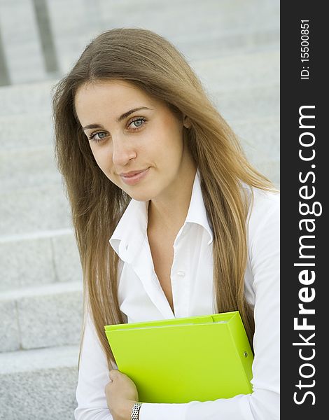Attractive young businesswoman smiling with a green folder on the chest. Attractive young businesswoman smiling with a green folder on the chest.