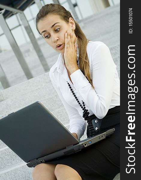 Business woman running on a laptop. He sits on the stairs office building. Business woman running on a laptop. He sits on the stairs office building