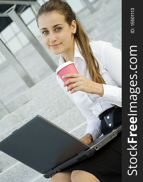 Young, beautiful woman business over coffee in the fresh air sitting on the stairs, office building, next to the laptop. Young, beautiful woman business over coffee in the fresh air sitting on the stairs, office building, next to the laptop.