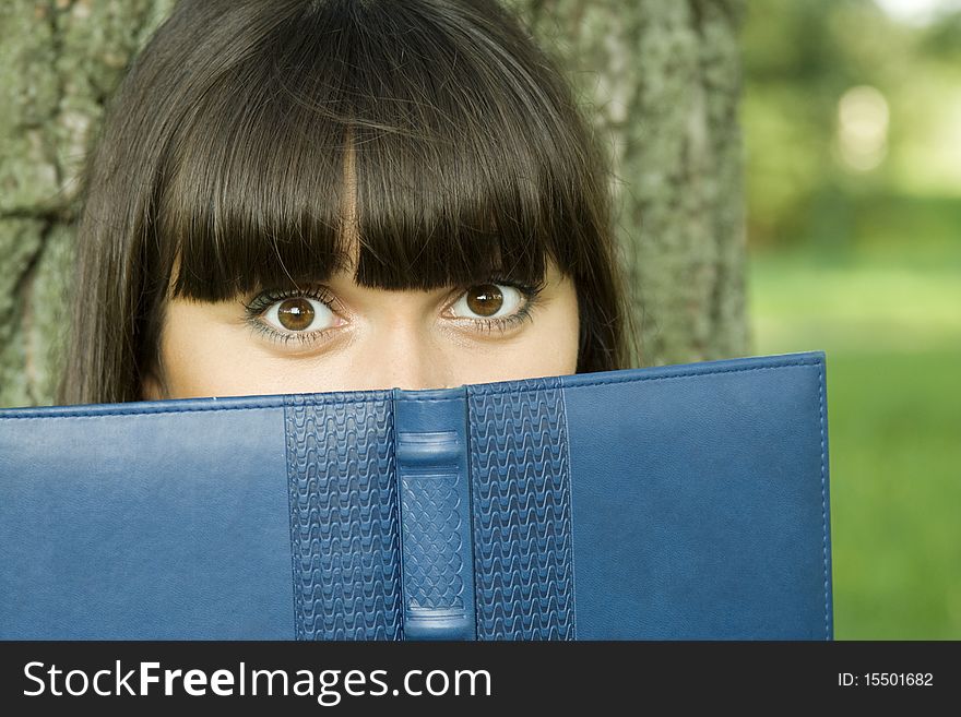 Young beautiful woman in a park with a notebook. Young beautiful woman in a park with a notebook