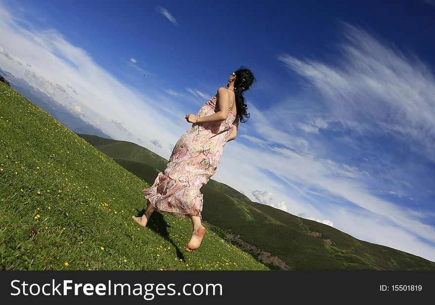 Girl is running under the blue sky on the grassland.