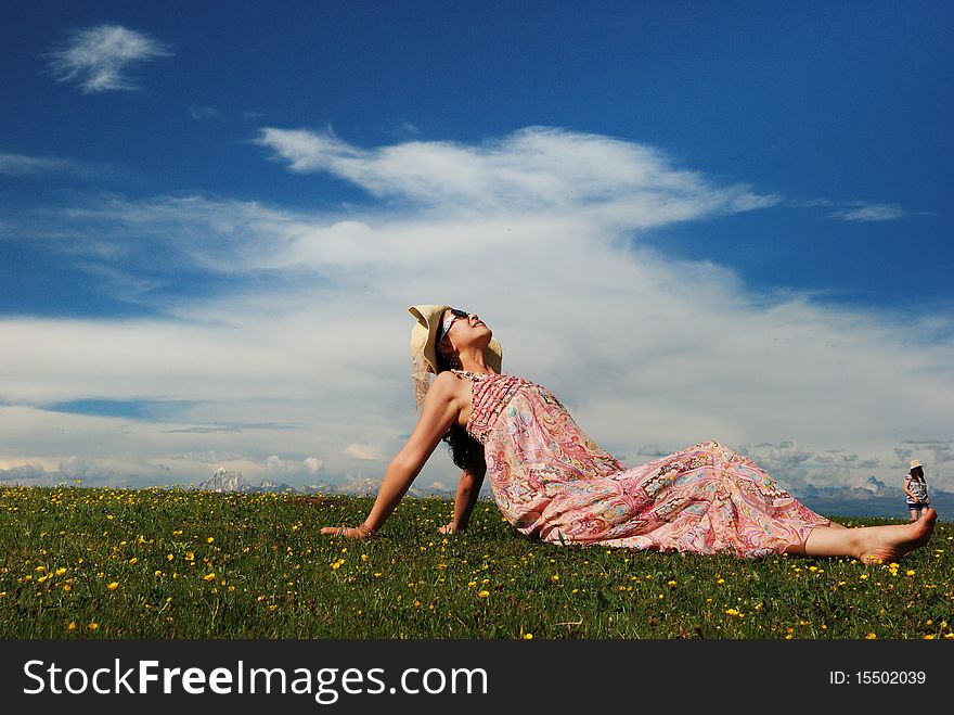Girl is lying under the blue sky on the grassland.