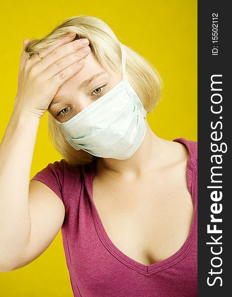 Young woman on a yellow background in a protective mask checks the temperature of hand. Young woman on a yellow background in a protective mask checks the temperature of hand