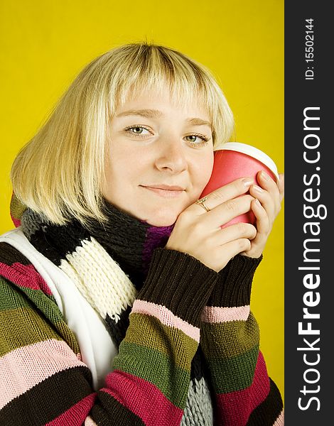 Young woman in sweater and scarf clasps to face a papercup of coffee. Winter. Young woman in sweater and scarf clasps to face a papercup of coffee. Winter
