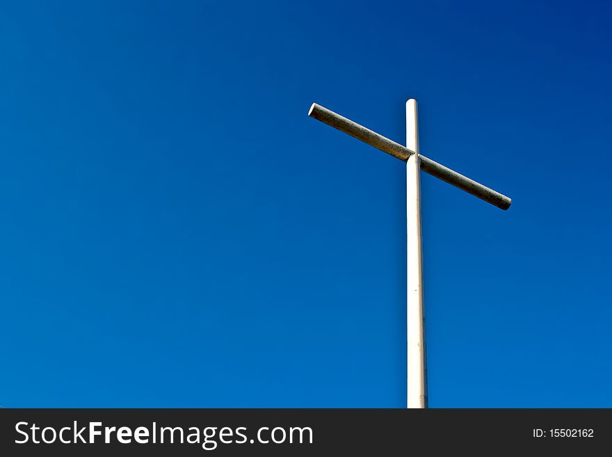 Under a deep blue sky stands a Cristian Cross made from welded pipe. Under a deep blue sky stands a Cristian Cross made from welded pipe.