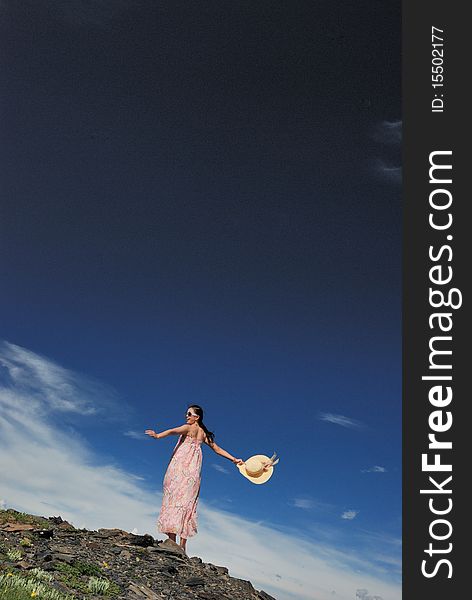 Girl is going round and round under the blue sky on the grassland.