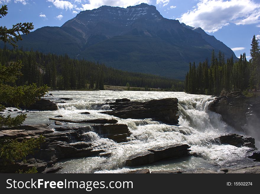 River flowing down a waterfall with the rocky mountains in the background. River flowing down a waterfall with the rocky mountains in the background