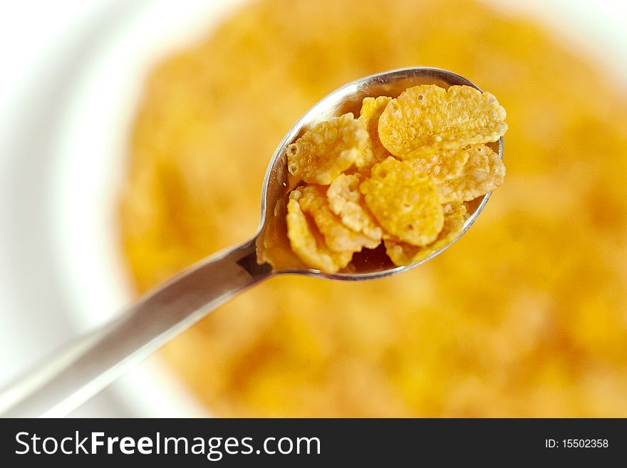 Cornflakes in a bowl and on a spoon. Selective focus photo.
