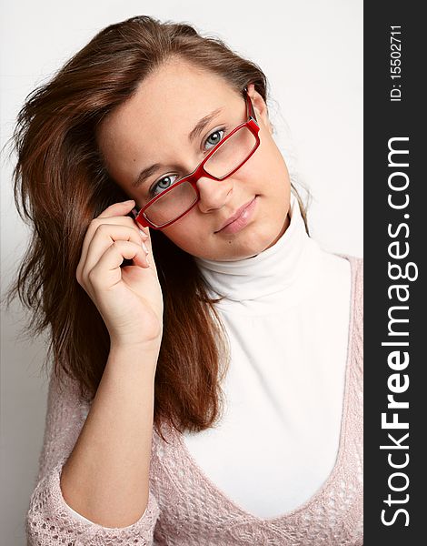 The beautiful girl with glasses on a light background