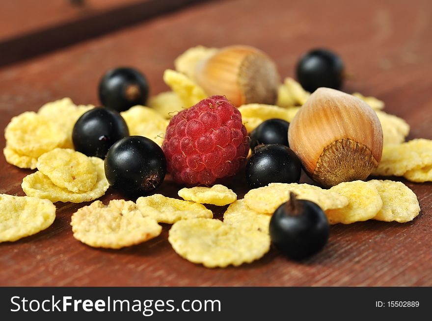 The corn flakes with berries on the wooden background. The corn flakes with berries on the wooden background