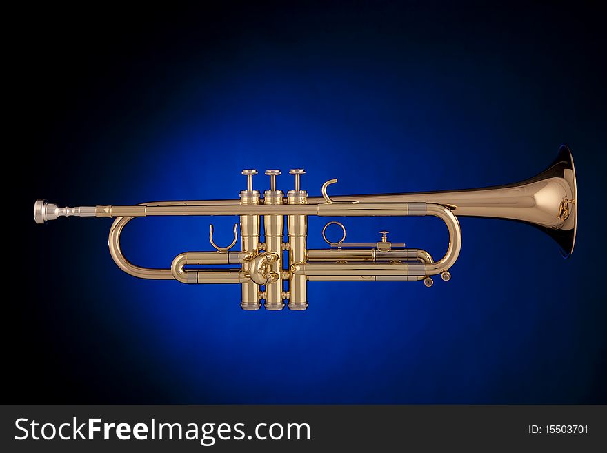A professional gold trumpet isolated against a spotlight blue background in the horizontal format. A professional gold trumpet isolated against a spotlight blue background in the horizontal format.