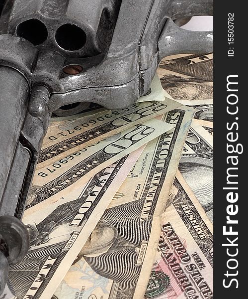A pistol rests on a stack of dollar bills. A pistol rests on a stack of dollar bills.