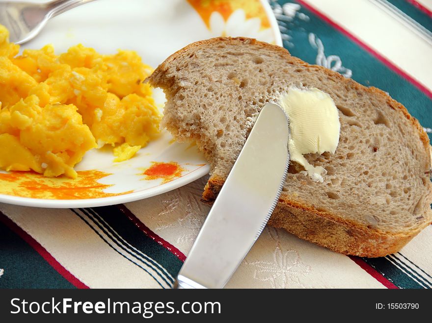 Knife on brown bread with butter and scrambled eggs served on table. Knife on brown bread with butter and scrambled eggs served on table
