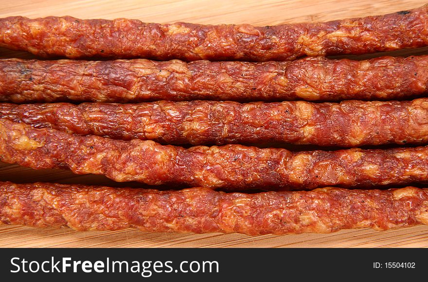 Smoked sausages on a wooden background in close up. Smoked sausages on a wooden background in close up