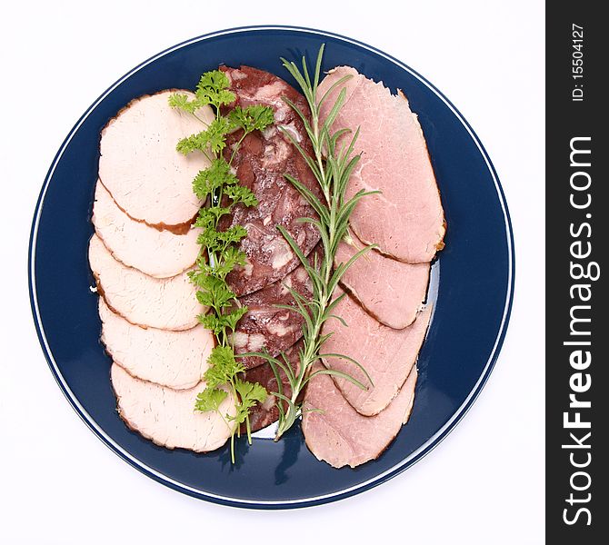 Plate of assorted cold cuts (ham, sirloin, headcheese) decorated with rosemary and parsley