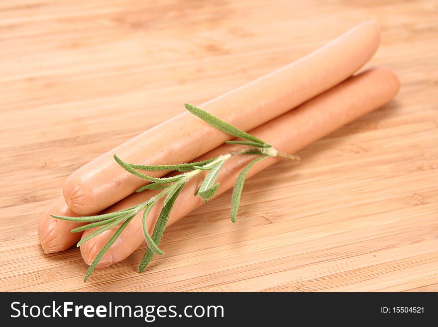 Hot dogs on a wooden background decorated with a rosemary twig