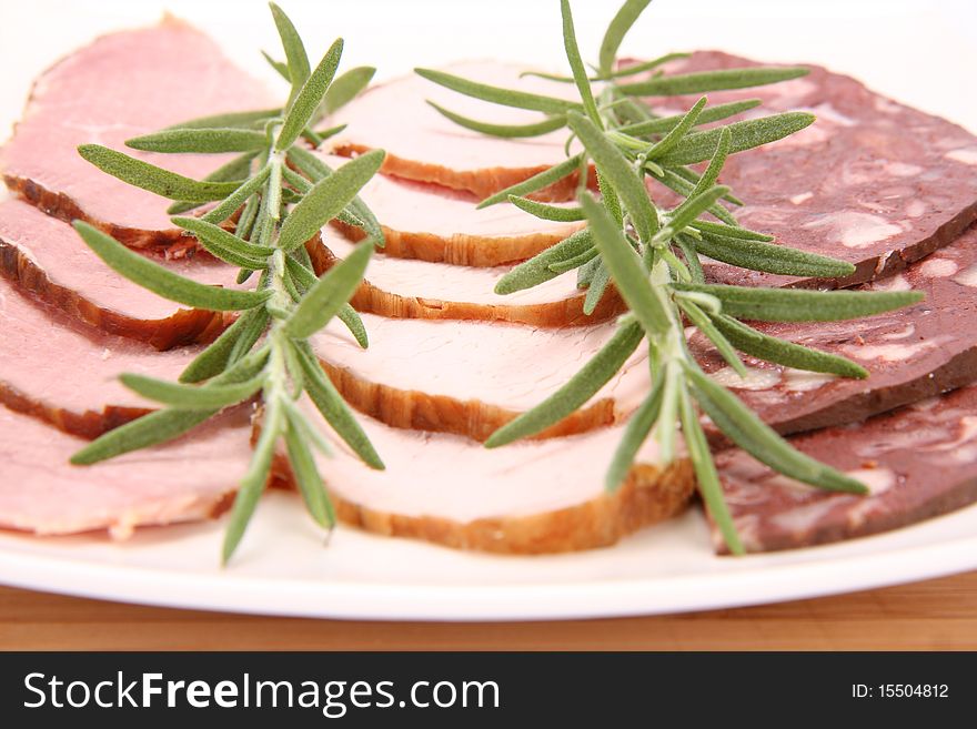 Plate of assorted cold cuts (ham, sirloin, headcheese) decorated with rosemary