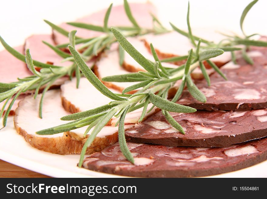 Plate of assorted cold cuts (ham, sirloin, headcheese) decorated with rosemary