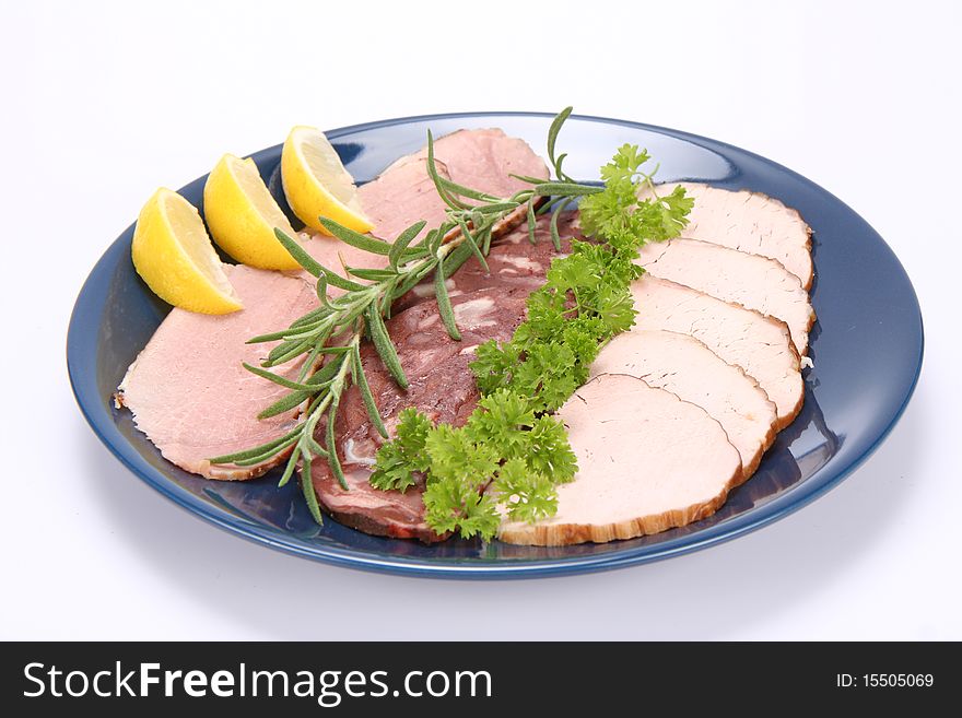 Plate of assorted cold cuts (ham, sirloin, headcheese) decorated with rosemary, parsley and lemon