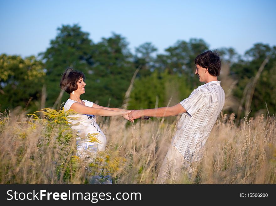 Happy pregnant woman dance in park with husband. Happy pregnant woman dance in park with husband