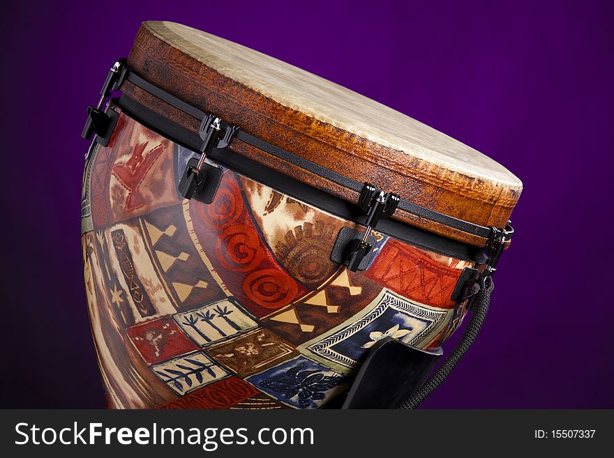An African Latin djembe or conga drum isolated against a spotlight purple background. An African Latin djembe or conga drum isolated against a spotlight purple background.