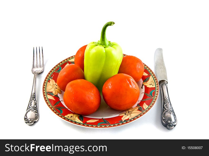 Peppers and tomatoes on plate on white bacground