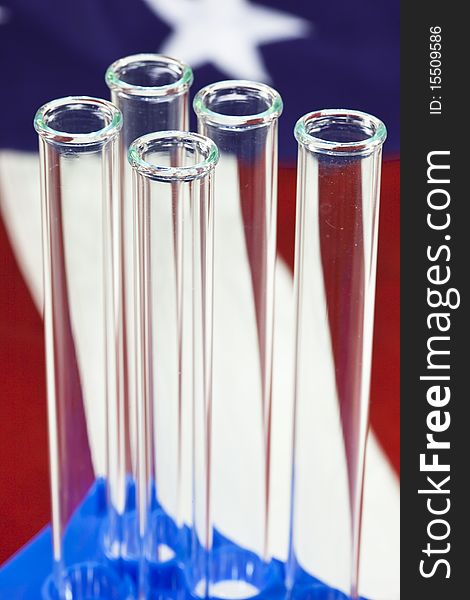 A Closeup of glass test tubes in rack with USA flag in background. A Closeup of glass test tubes in rack with USA flag in background