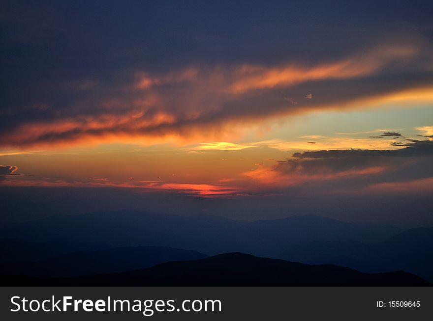 Shutting down of sky. Orange clouds over blue mountains. Shutting down of sky. Orange clouds over blue mountains.