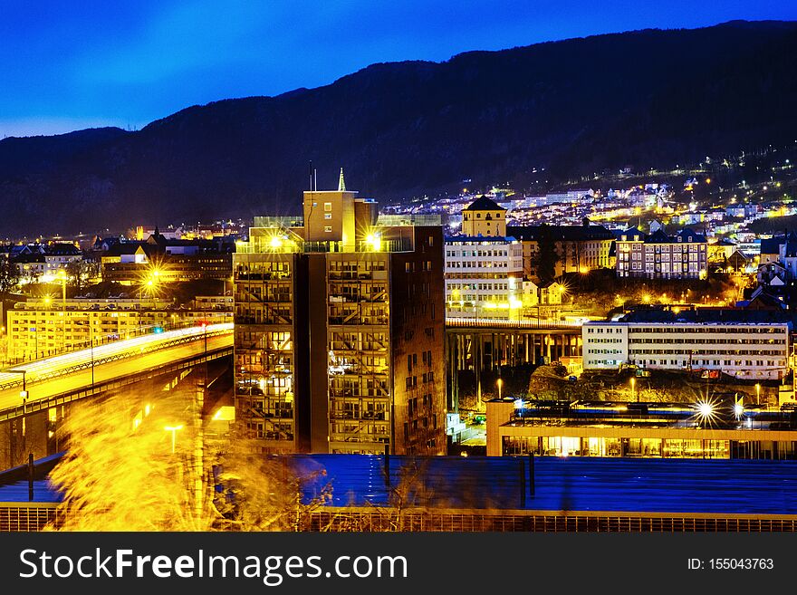 View of Bergen, Norway at night. Colorful cloudy blue sky over the mountains