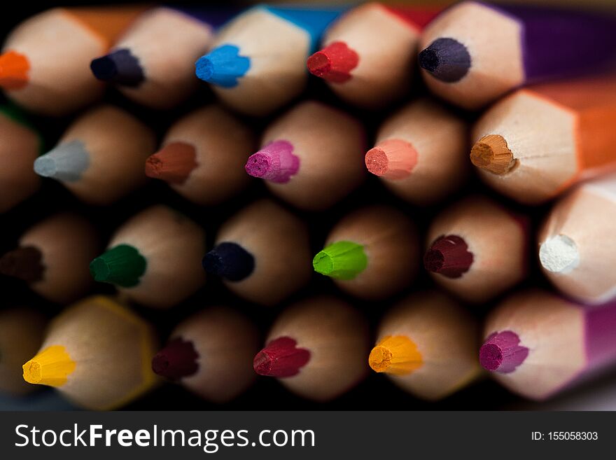 Wooden pencils in all colors seen from the sheet of pencils. Colored pencils stacked with a black background. Colors. Back to