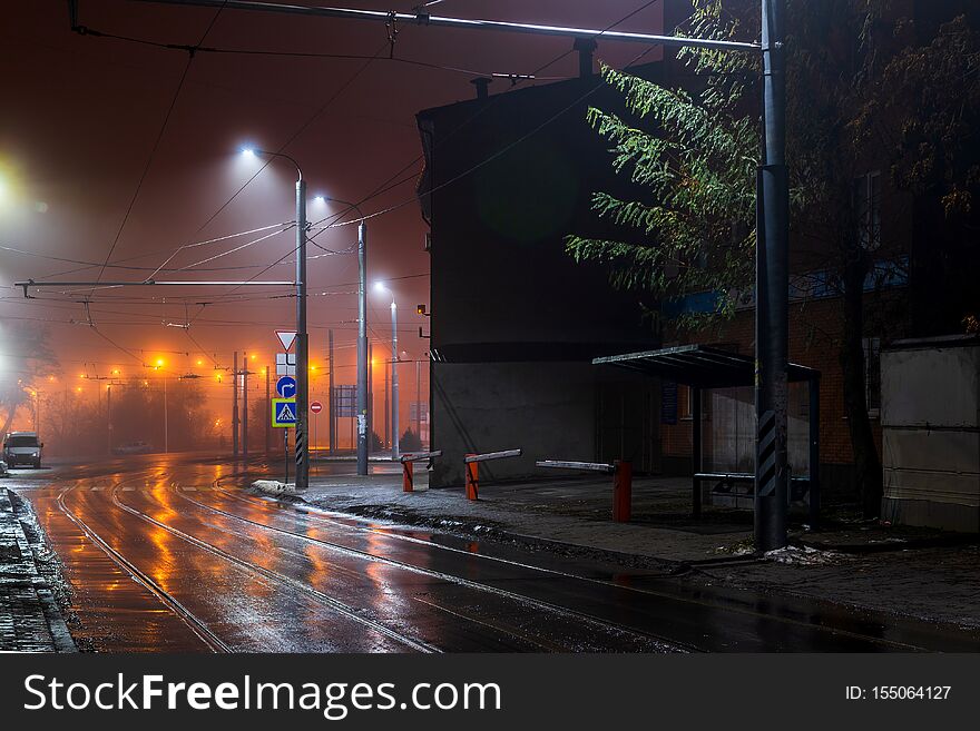 Street lights foggy misty night. Tram route on a city street