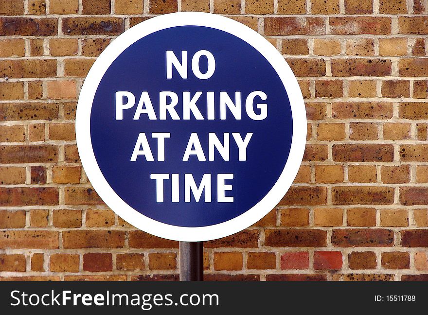 Round blue sign for no parking with a brickwall in the background