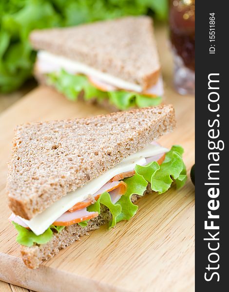 Close up of freshly made sandwich with dietetic bread on wooden cutting board. Close up of freshly made sandwich with dietetic bread on wooden cutting board