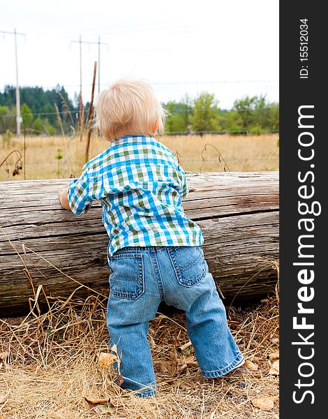 A young one year old kid in a rural field wearing a plaid shirt with blue eyes and blonde hair. A young one year old kid in a rural field wearing a plaid shirt with blue eyes and blonde hair.