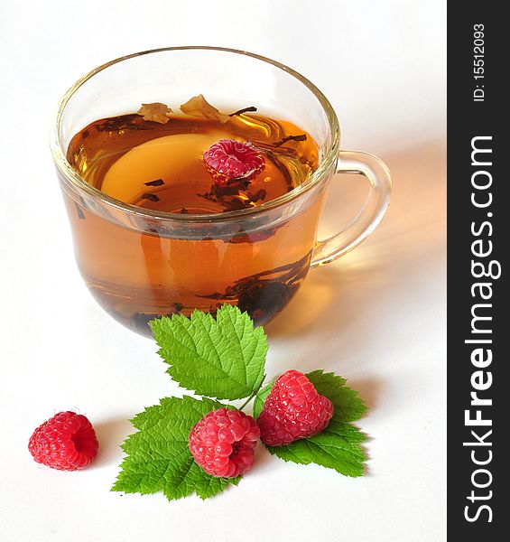 Tea is brewed in a cup, near the cup of berry. Tea is brewed in a cup, near the cup of berry