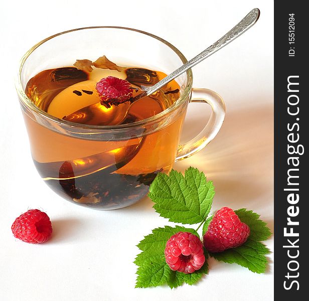 Tea is brewed in a cup, near the cup of berry. Tea is brewed in a cup, near the cup of berry