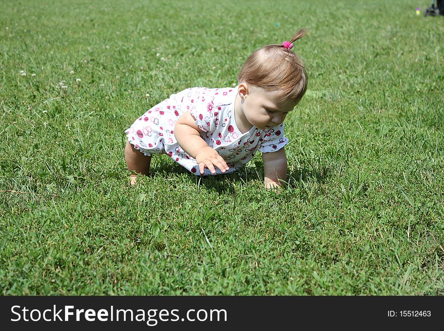 Child is sitting on the green grass