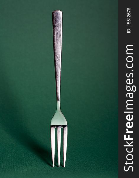 Metal fork isolated on green background