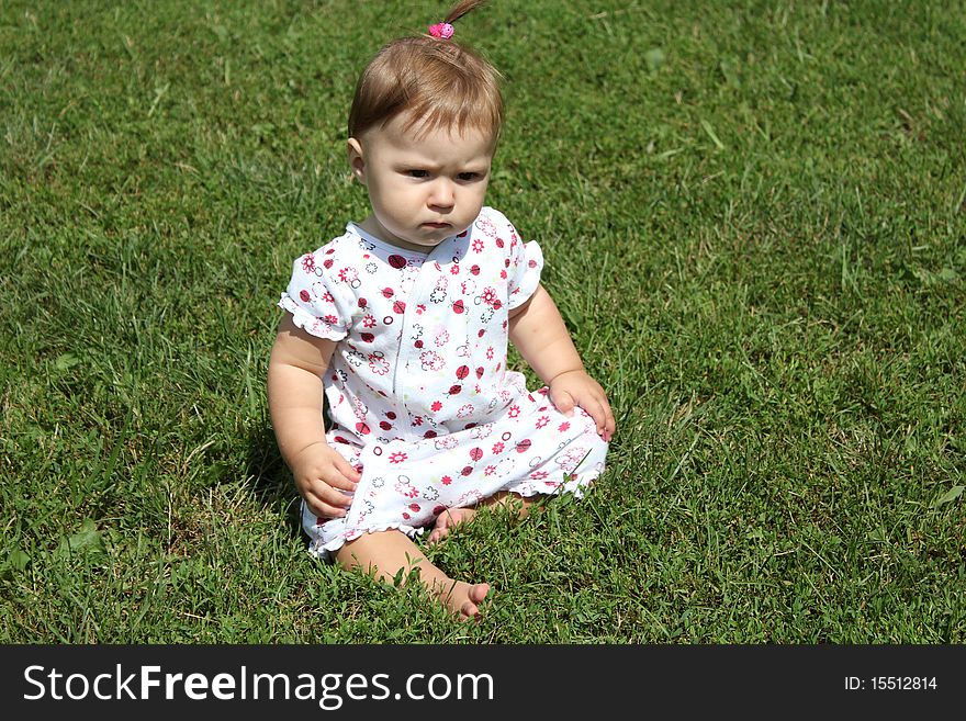 Child is sitting on the green grass