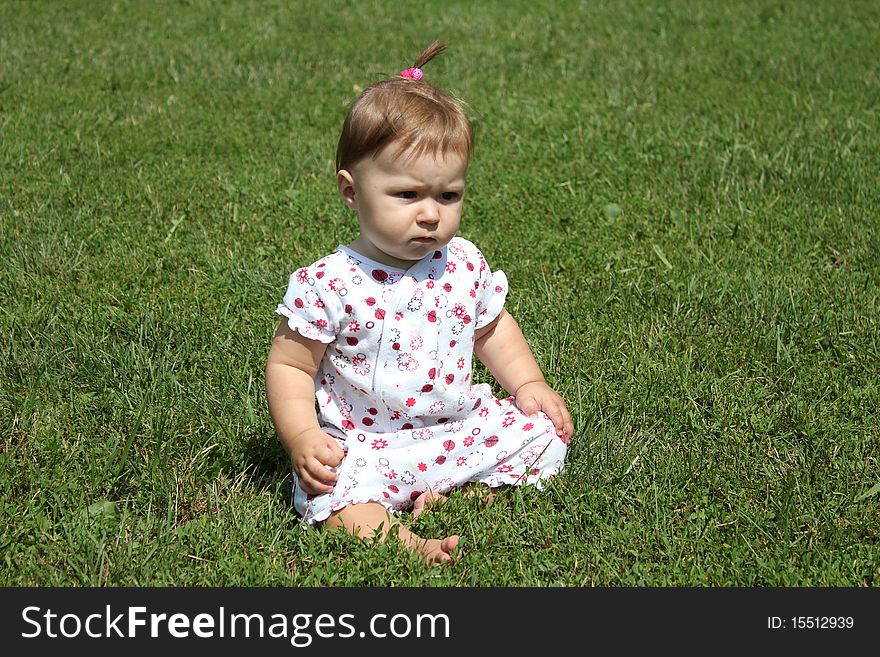 The child joyfully sits on a grass