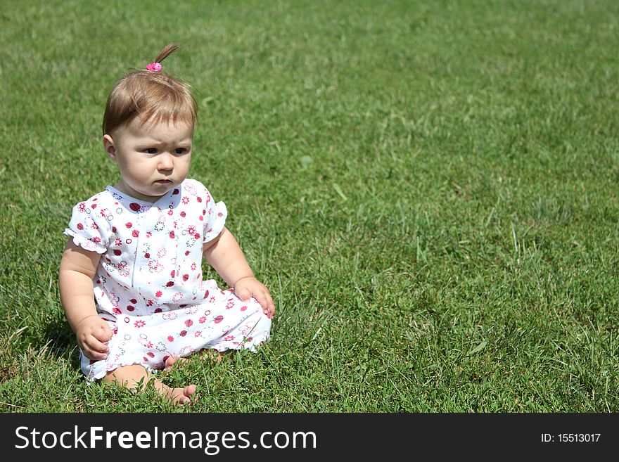 Child is sitting on the green grass
