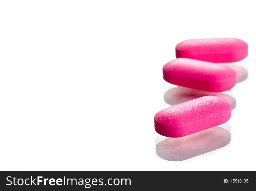 Extreme close-up of pink pills isolated on white background