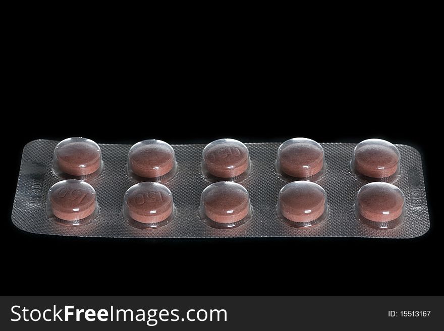 Closeup of a pack of brown pills isolated on black 

background