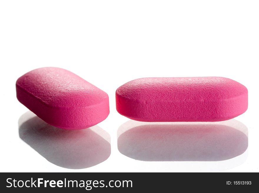 Extreme close-up of pink pills isolated on white background