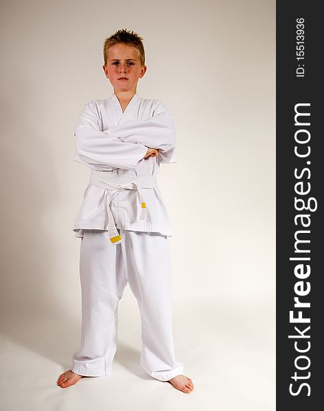 A vertical image of a young teenage boy in karate suit standing with arms folded and a serious look on his face, isolated against a plain background. A vertical image of a young teenage boy in karate suit standing with arms folded and a serious look on his face, isolated against a plain background