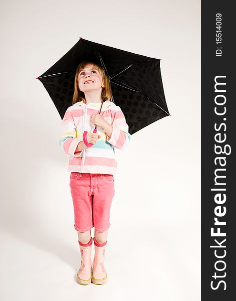 A vertical image isolated on plain background, lovely cute little girl, blonde big blue eyes, looking out from under her umbrella, wearing pink rainwear. A vertical image isolated on plain background, lovely cute little girl, blonde big blue eyes, looking out from under her umbrella, wearing pink rainwear