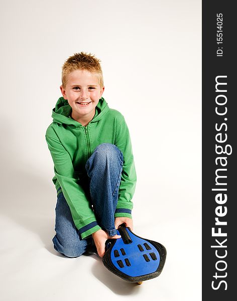 A vertical image isolated on plain background,teenage boy kneeling beside waveboard,handsome and smiling. A vertical image isolated on plain background,teenage boy kneeling beside waveboard,handsome and smiling